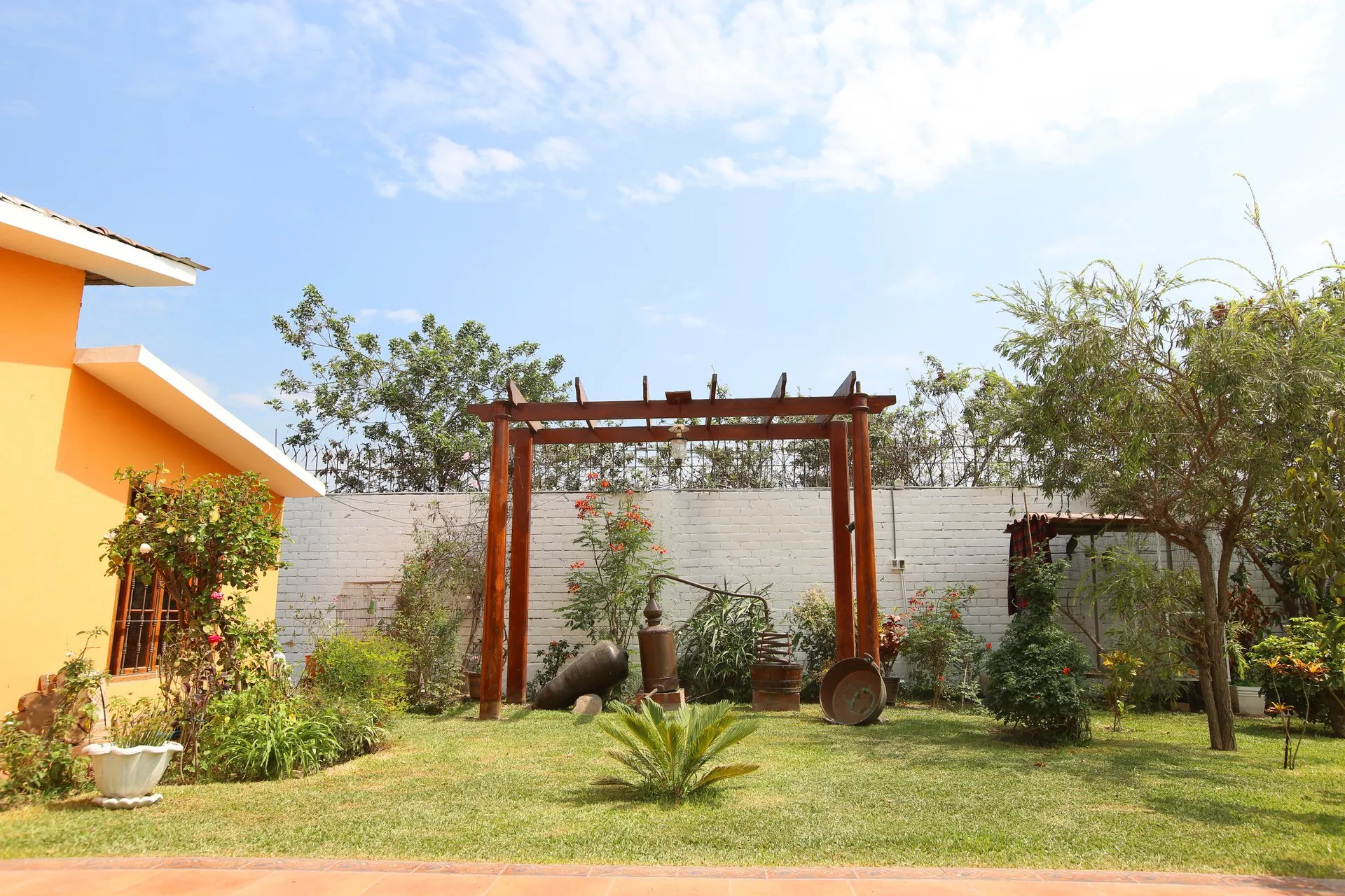 Pérgola de madera en jardín lateral con decoración