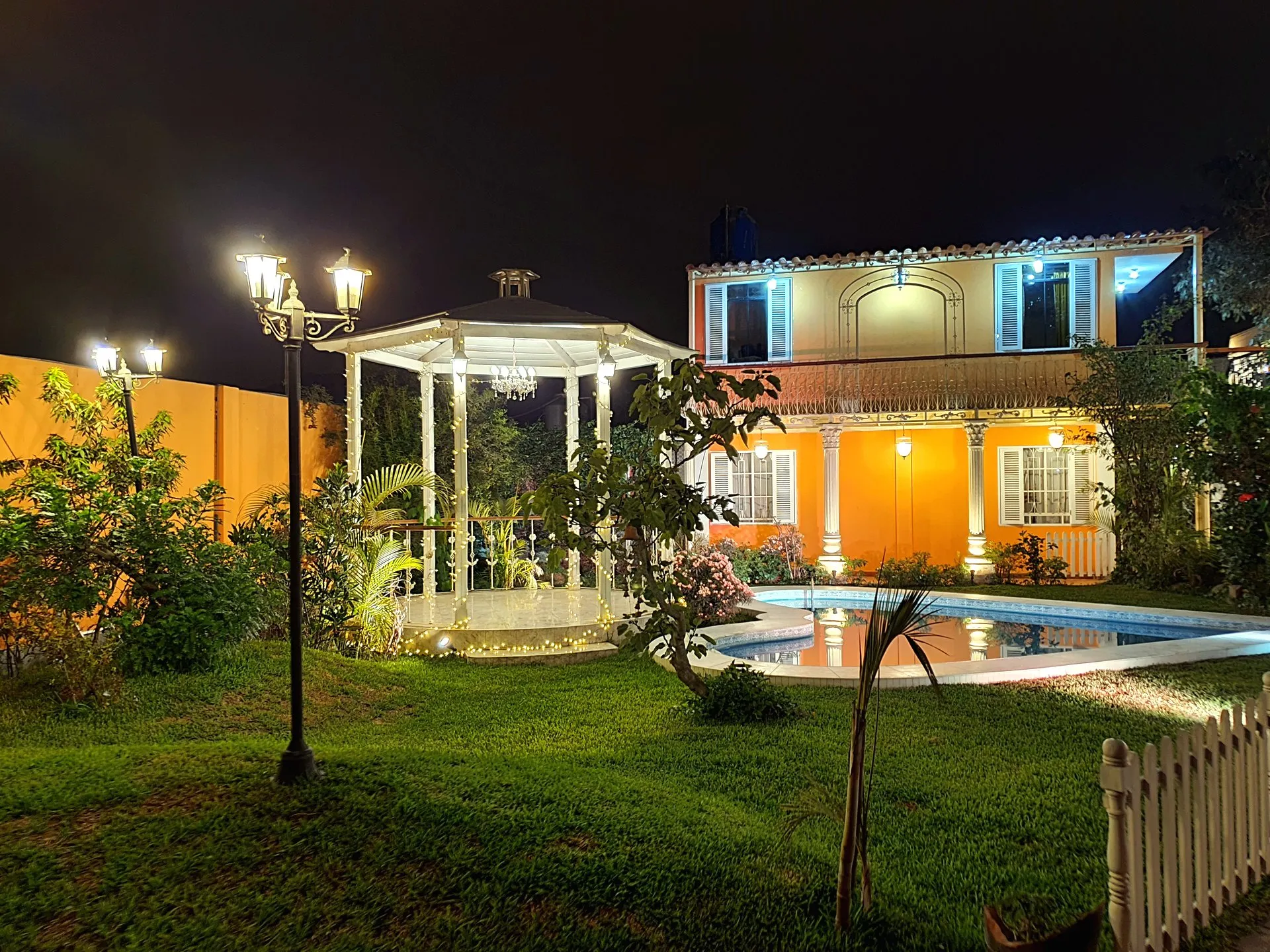 Glorieta blanca iluminada al anochecer en Casa Villa Marlene